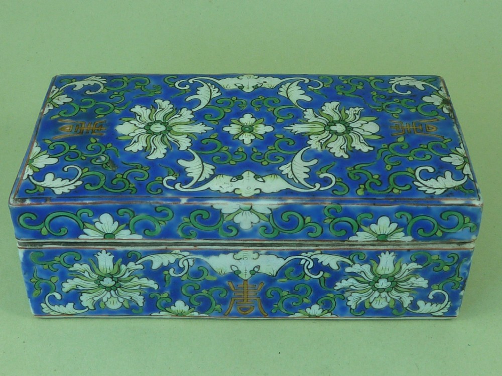 A rectangular Chinese porcelain pen box decorated with lotus scrolls and auspicious symbols in green and white enamels over a cobalt blue ground. View II