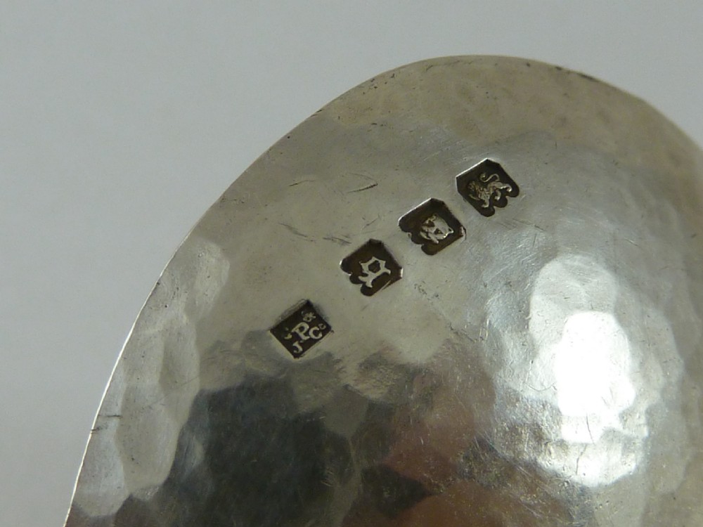 A sterling silver caddy spoon featuring a circular bowl, hammered surface finish, and a flared handle with a pierced geometric motif. View III