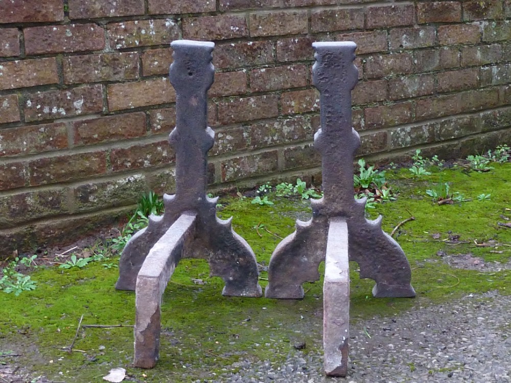 A pair of heavy cast iron Elizabethan fire dogs featuring upright columnar shafts, raised date markings, and broad arched legs. View IX