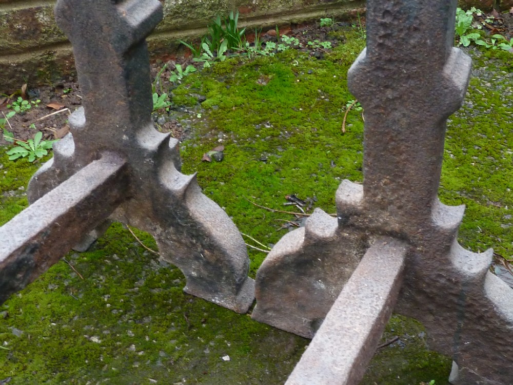 A pair of heavy cast iron Elizabethan fire dogs featuring upright columnar shafts, raised date markings, and broad arched legs. View XI