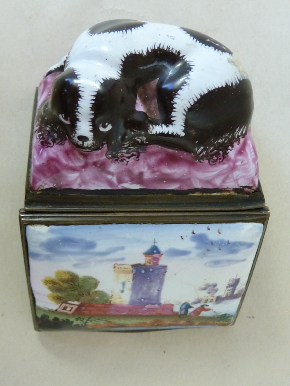 An eighteenth-century Bilston enamel snuff box depicting a black and white King Charles spaniel curled on a magenta cushion base with metal mounts. View II