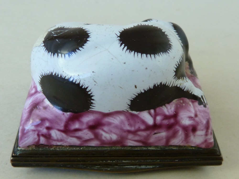 An eighteenth-century Bilston enamel snuff box depicting a black and white King Charles spaniel curled on a magenta cushion base with metal mounts. View V