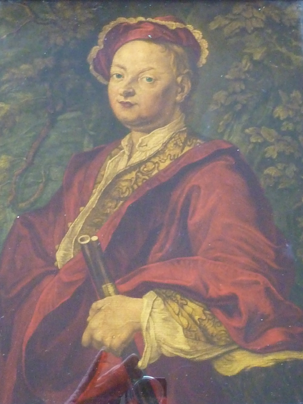 An 18th-century Georgian reverse glass painted portrait featuring a gentleman in a red robe holding a gun barrel within a dark moulded frame. View III