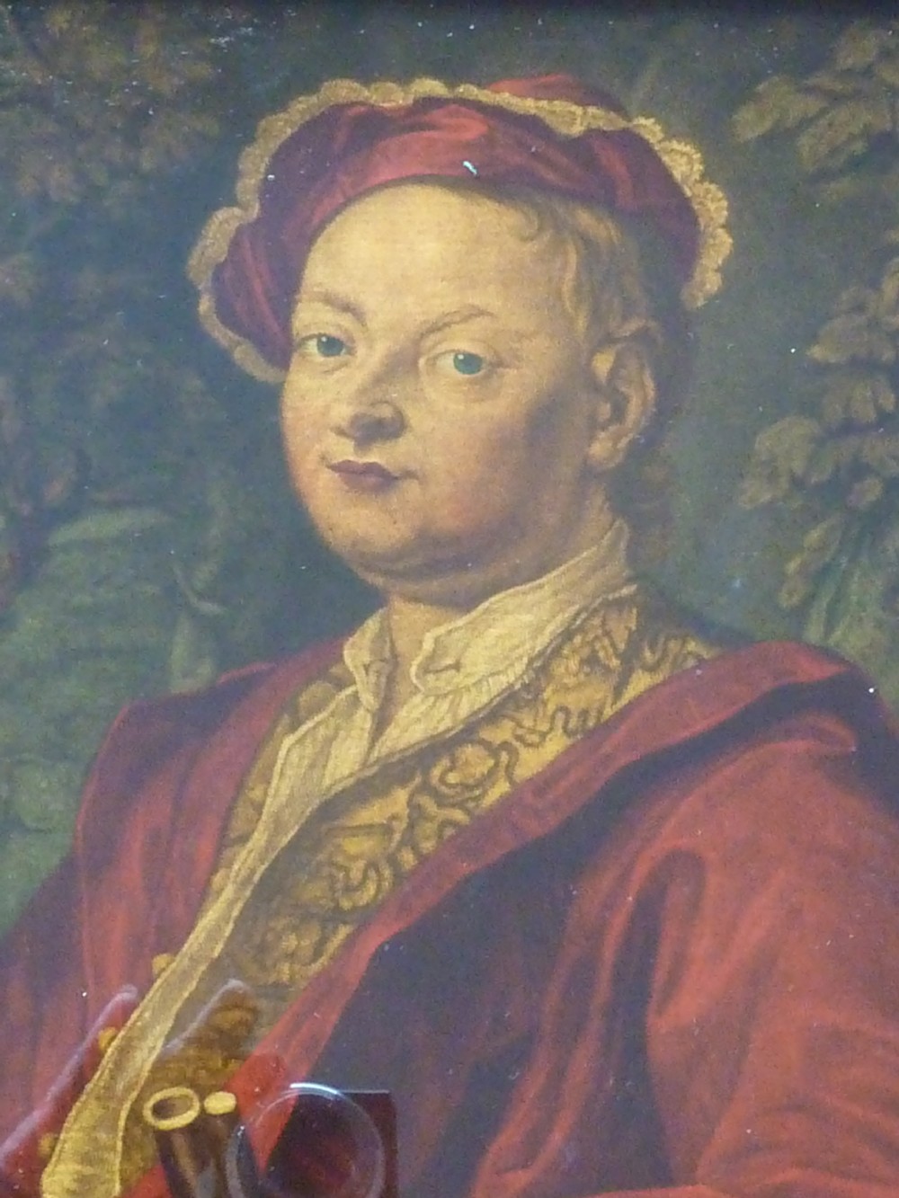 An 18th-century Georgian reverse glass painted portrait featuring a gentleman in a red robe holding a gun barrel within a dark moulded frame. View IV