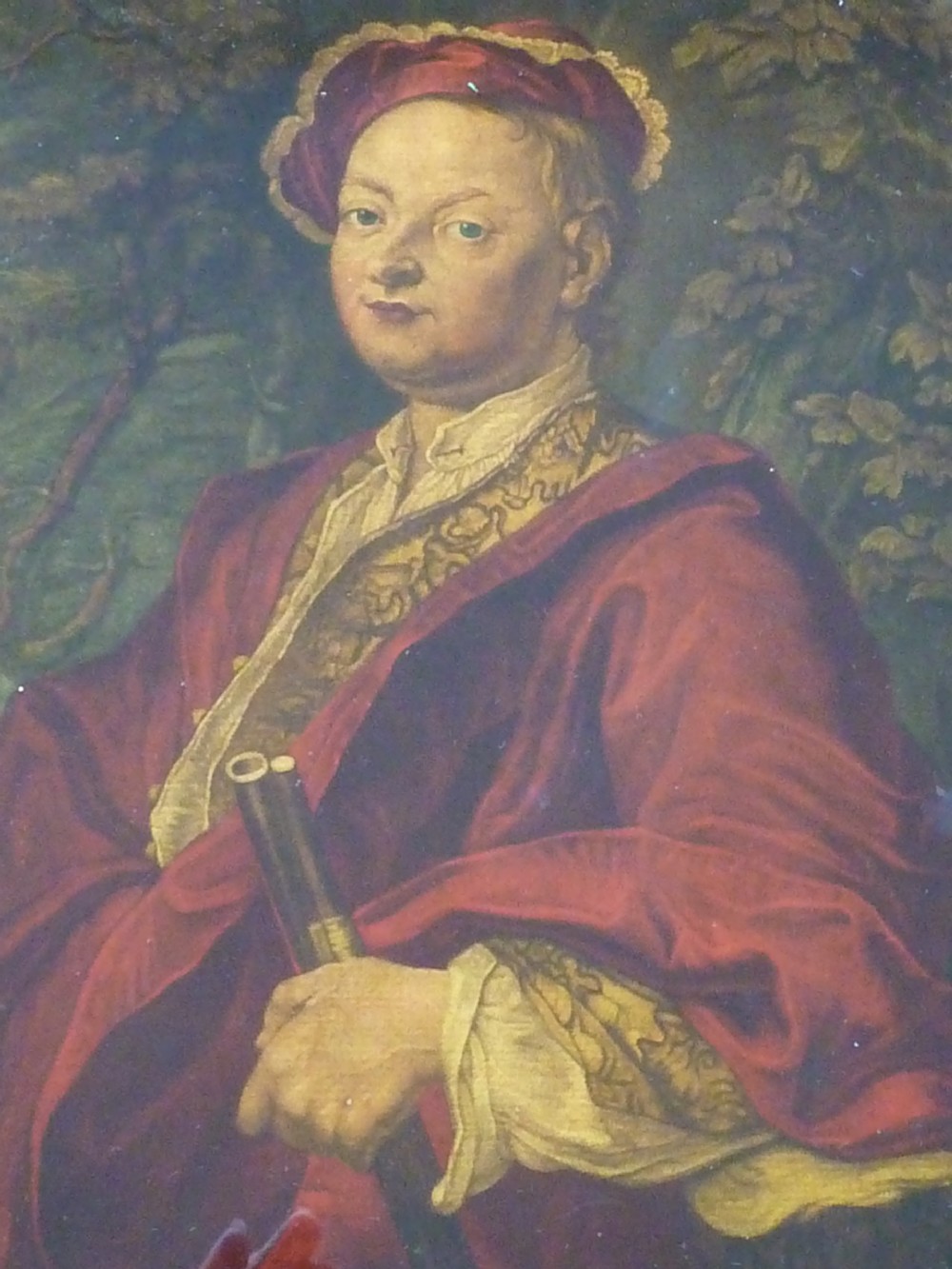 An 18th-century Georgian reverse glass painted portrait featuring a gentleman in a red robe holding a gun barrel within a dark moulded frame. View V