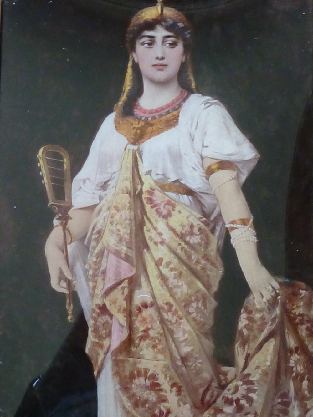 A framed Victorian chrystoleum reverse glass print depicting a figure in Egyptian Revival attire holding a musical instrument inside a gilded wooden frame. View III