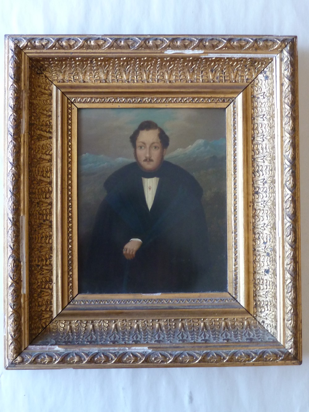 A pair of 19th-century naive portrait paintings on tinplate depicting a man and a woman, framed in heavy carved gilt frames. View II