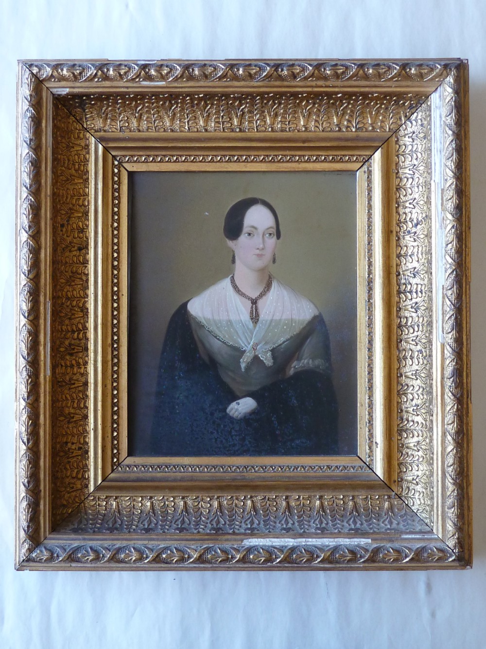 A pair of 19th-century naive portrait paintings on tinplate depicting a man and a woman, framed in heavy carved gilt frames. View IV