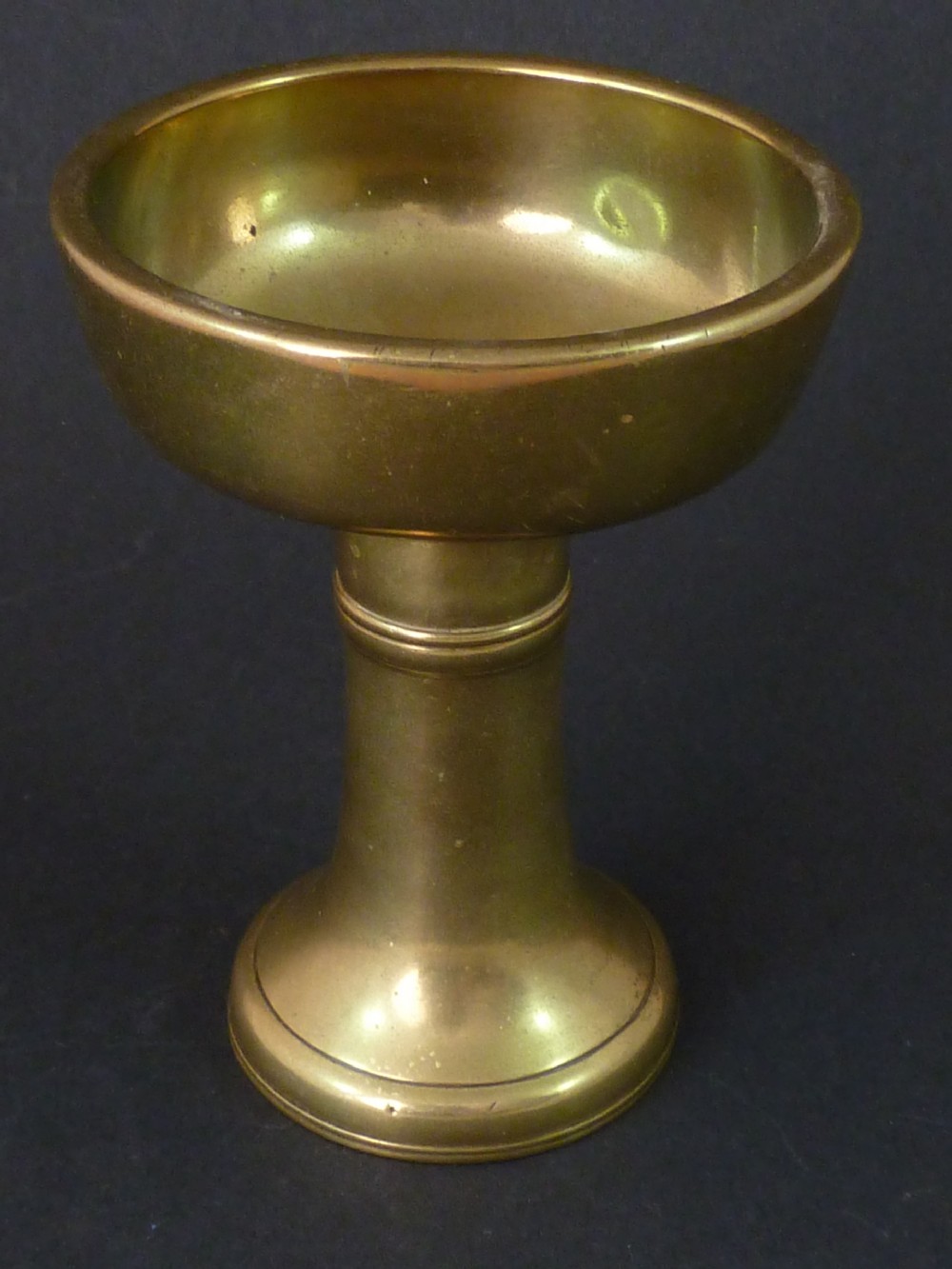 A solid brass Tibetan butter lamp displaying a flared circular base, knopped stem, and wide shallow rimmed upper bowl. View III