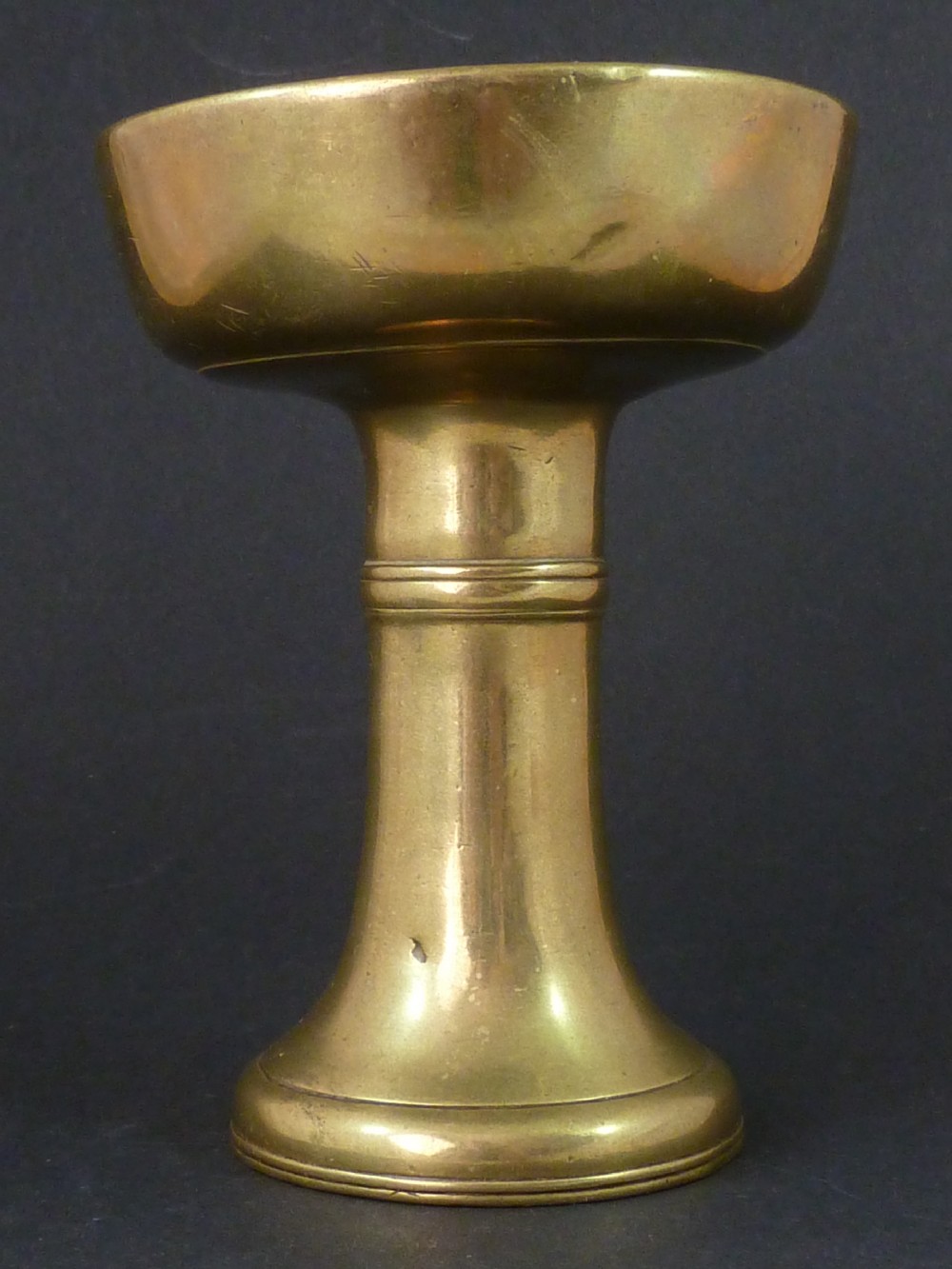 A solid brass Tibetan butter lamp displaying a flared circular base, knopped stem, and wide shallow rimmed upper bowl. View V