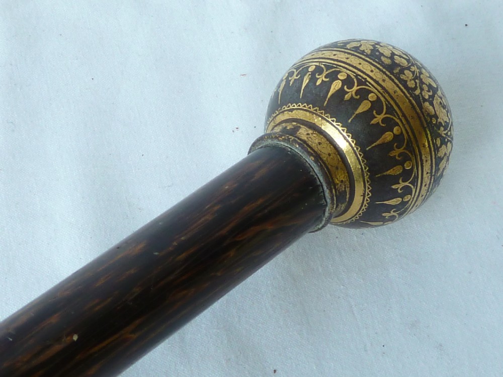 An antique walking stick featuring a round steel ball handle with intricate gold damascene inlay mounted on a dark palm wood shaft. View VI