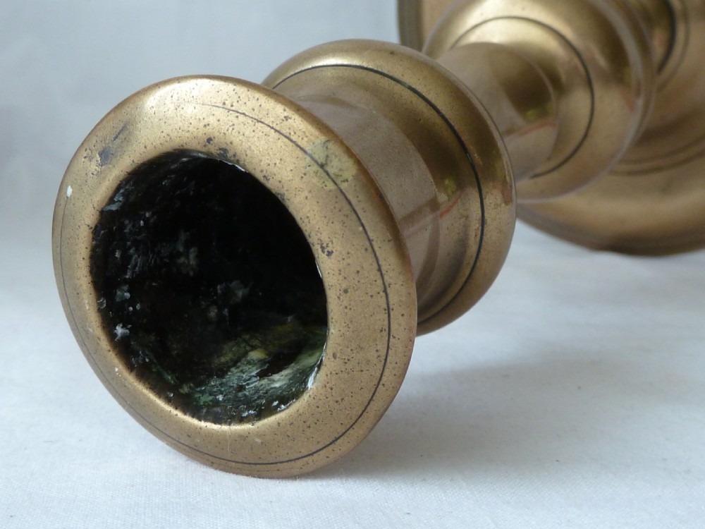 A turned cast brass candlestick featuring a wide circular base, a central knop stem, and a single socket with an extraction hole. View VIII