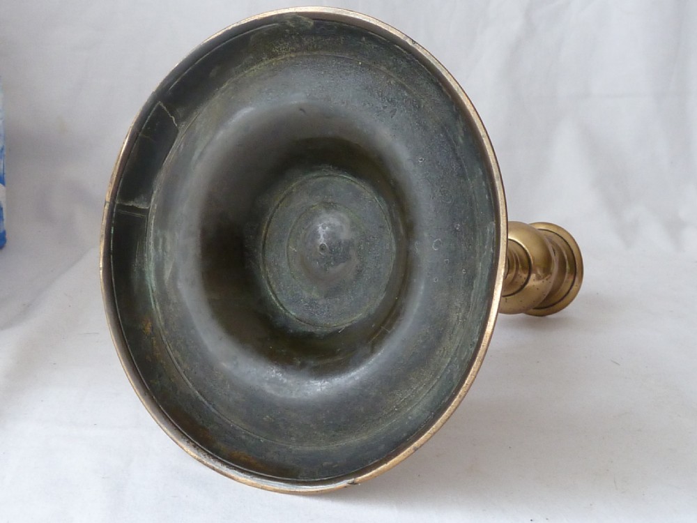 A turned cast brass candlestick featuring a wide circular base, a central knop stem, and a single socket with an extraction hole. View IX