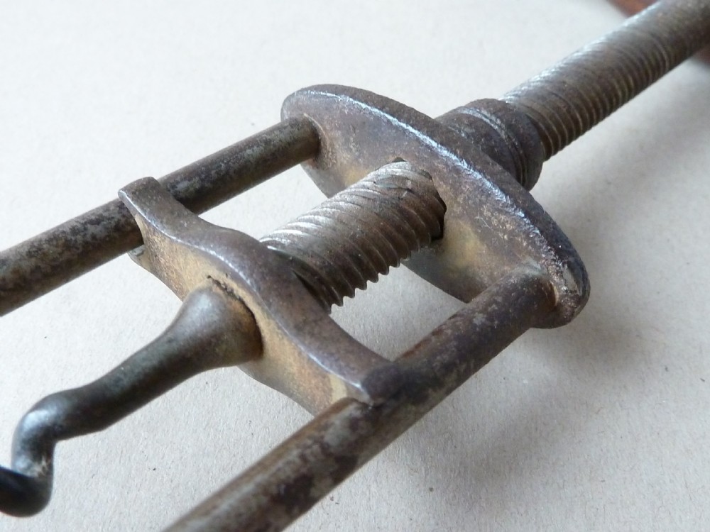 An antique English steel two-pillar corkscrew featuring a central threaded shaft, wire helix, and a turned dark rosewood handle fitted with a small dusting brush. View IV