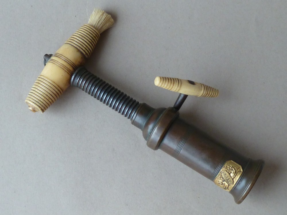 An antique dark bronze Thomason patent corkscrew featuring a turned bone handle, side key, detachable bristle brush, and an applied brass crest. View III