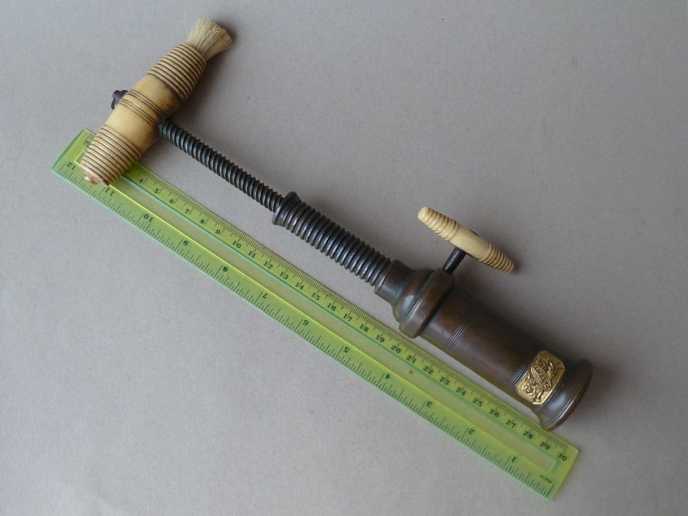 An antique dark bronze Thomason patent corkscrew featuring a turned bone handle, side key, detachable bristle brush, and an applied brass crest. View IV