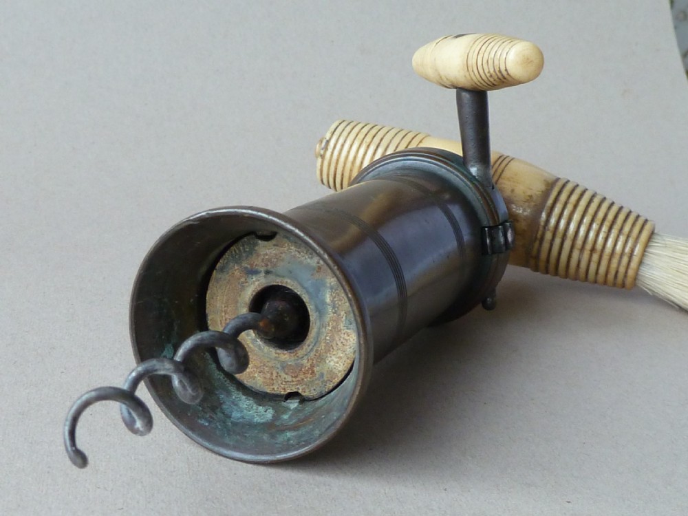 An antique dark bronze Thomason patent corkscrew featuring a turned bone handle, side key, detachable bristle brush, and an applied brass crest. View V