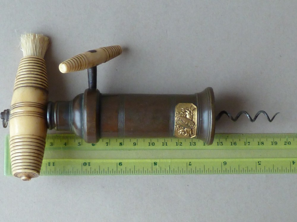 An antique dark bronze Thomason patent corkscrew featuring a turned bone handle, side key, detachable bristle brush, and an applied brass crest. View VI
