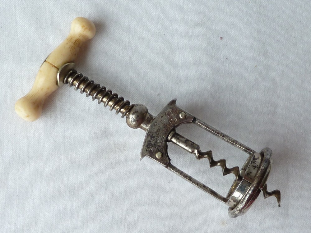 An antique German Columbus mechanical steel corkscrew featuring a carved bone T-handle and a tension spring shaft. View II