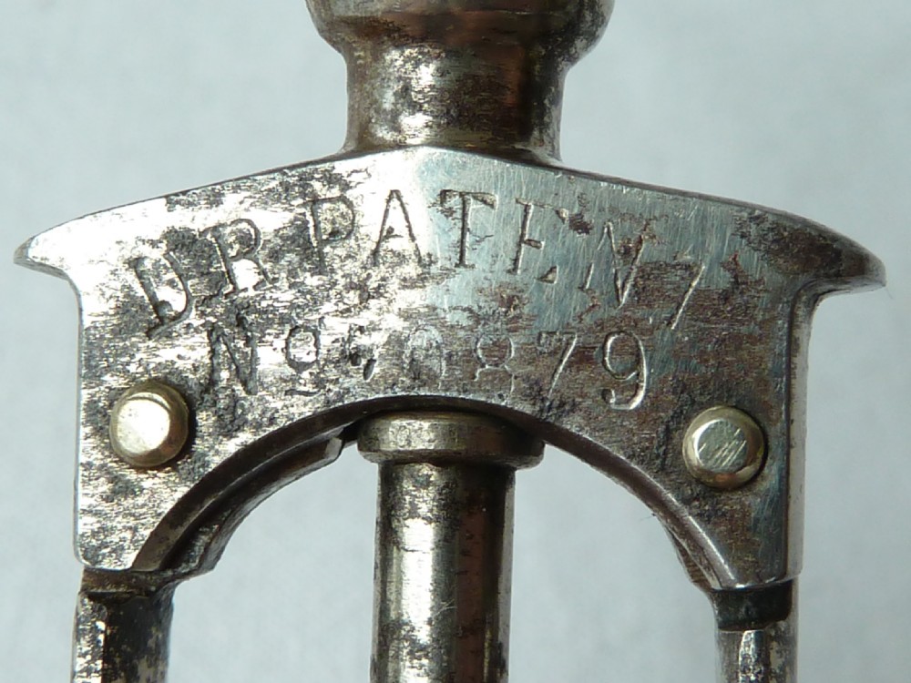 An antique German Columbus mechanical steel corkscrew featuring a carved bone T-handle and a tension spring shaft. View IV