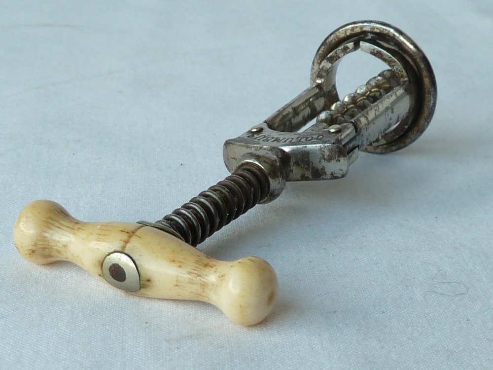 An antique German Columbus mechanical steel corkscrew featuring a carved bone T-handle and a tension spring shaft. View VII