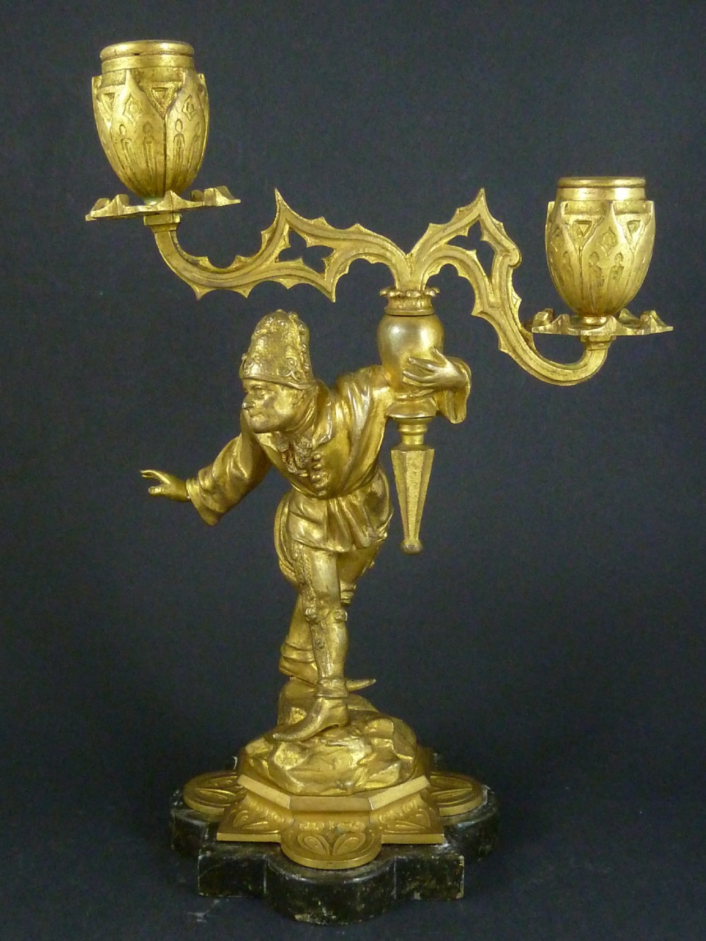 A pair of gilt bronze twin-light figural candelabra featuring sculpted Renaissance figures supporting branching candle arms set upon dark marble bases. View II