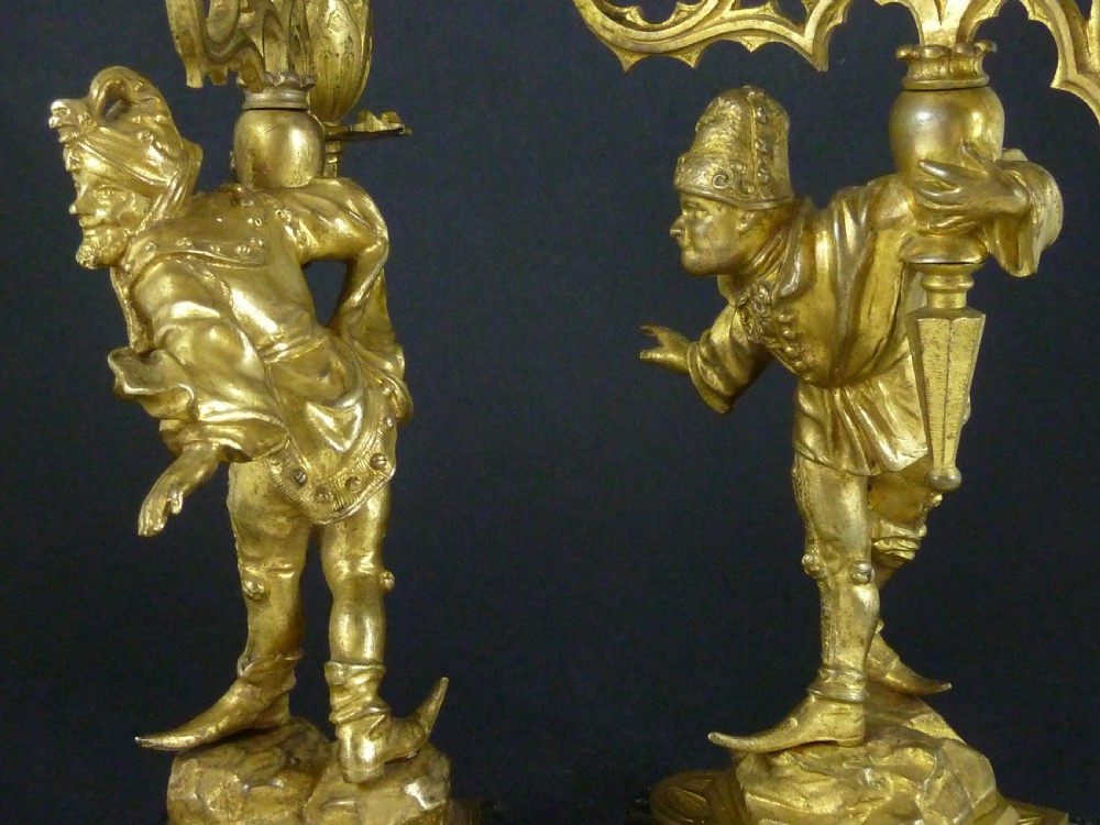 A pair of gilt bronze twin-light figural candelabra featuring sculpted Renaissance figures supporting branching candle arms set upon dark marble bases. View X