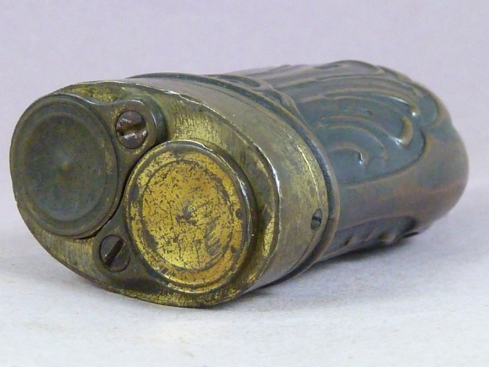 An antique embossed copper and brass three-way pistol flask featuring a central palmette design and a top dispensing nozzle. View V