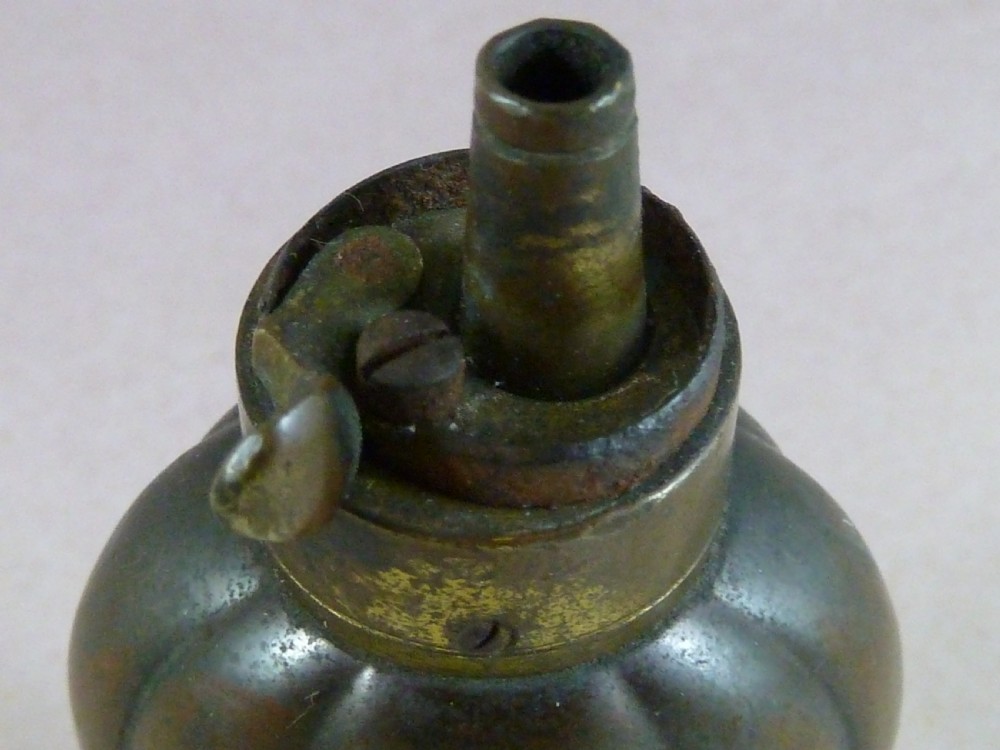 An antique embossed copper and brass three-way pistol flask featuring a central palmette design and a top dispensing nozzle. View VI