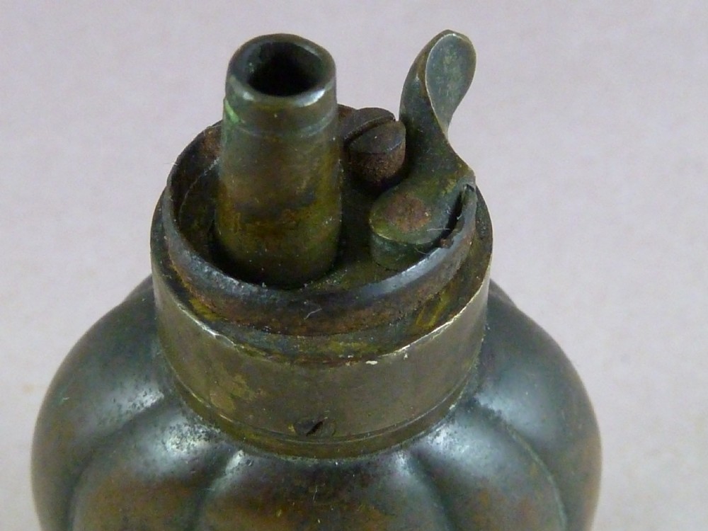 An antique embossed copper and brass three-way pistol flask featuring a central palmette design and a top dispensing nozzle. View VIII