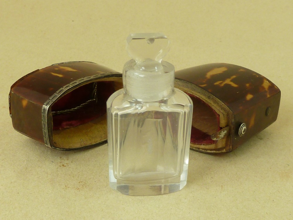 An opened Georgian tortoiseshell etui case lined with red velvet, containing a small clear glass perfume bottle with a faceted stopper. View II