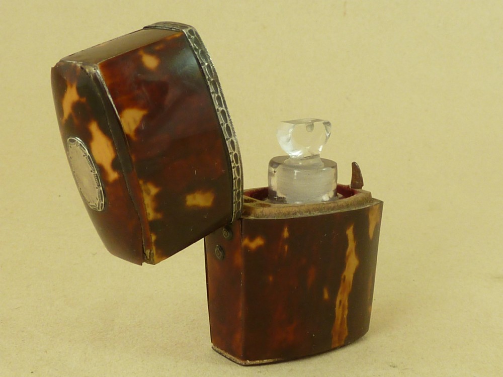 An opened Georgian tortoiseshell etui case lined with red velvet, containing a small clear glass perfume bottle with a faceted stopper. View III