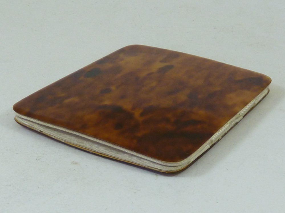 A closed two-panel Art Deco magic wallet with a mottled amber brown tortoiseshell exterior and rounded edges. View VII