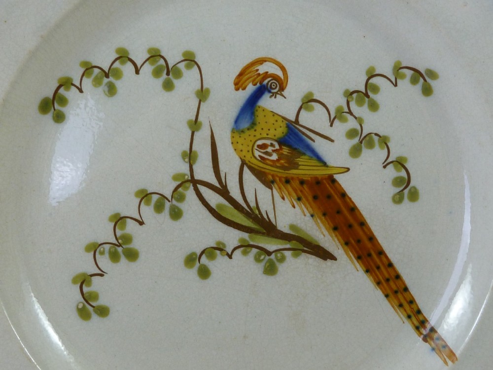 An antique pearlware plate featuring a hand-painted peafowl on a branch framed by a blue feather-edge rim. View II