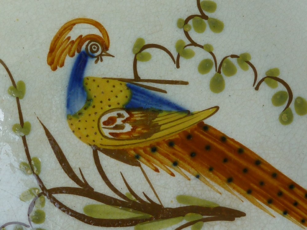 An antique pearlware plate featuring a hand-painted peafowl on a branch framed by a blue feather-edge rim. View IV