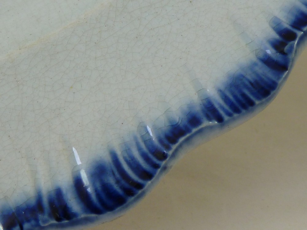 An antique pearlware plate featuring a hand-painted peafowl on a branch framed by a blue feather-edge rim. View V