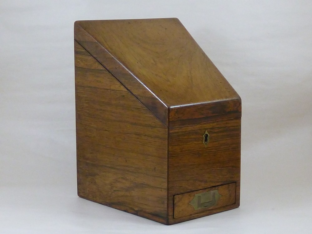 A Victorian rosewood sloping desktop stationery cabinet with open hinged lid revealing tiered light-wood compartments and a lower drawer with brass handle. View II