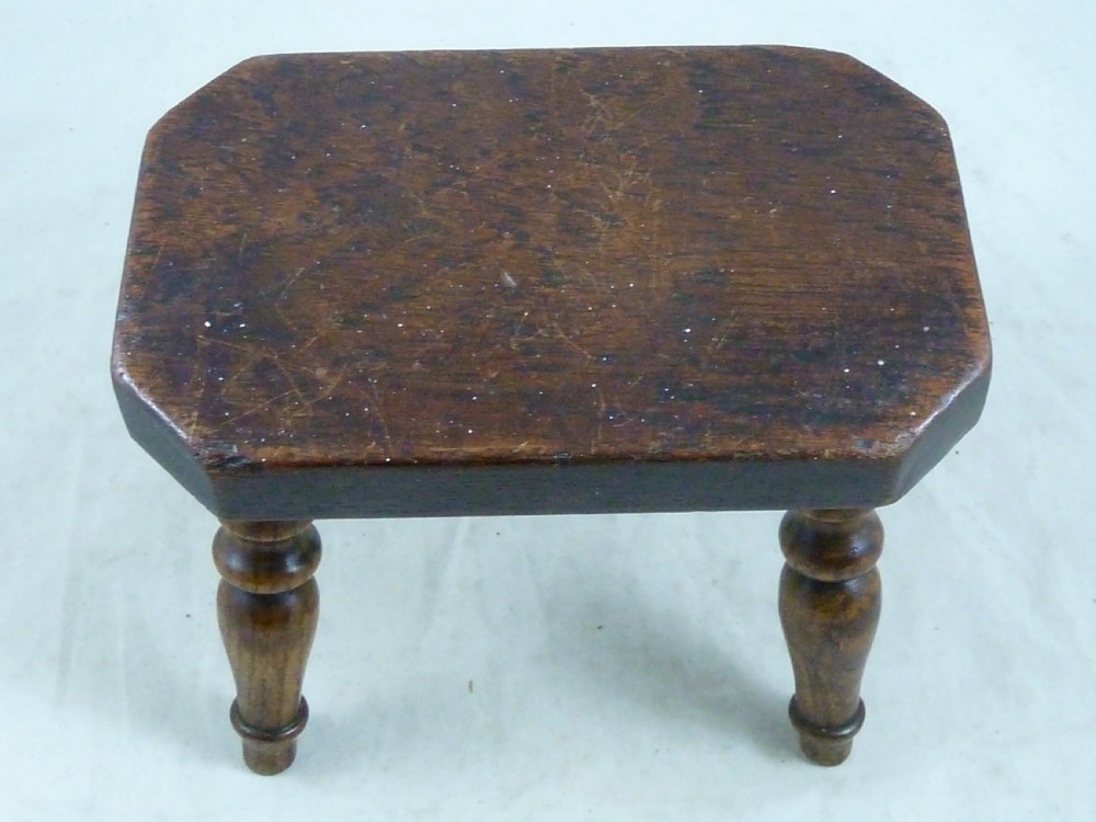 A small antique dark wooden stool featuring a rectangular top and four turned baluster legs. View IV