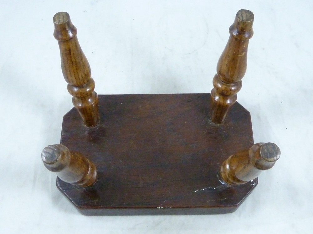 A small antique dark wooden stool featuring a rectangular top and four turned baluster legs. View V