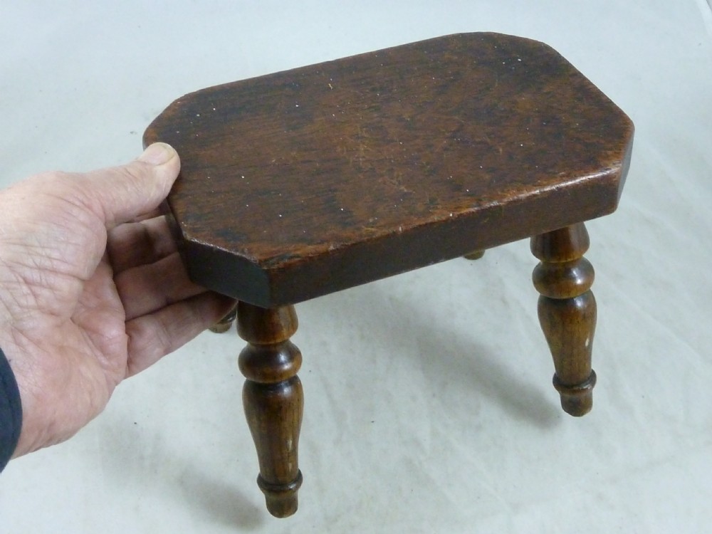 A small antique dark wooden stool featuring a rectangular top and four turned baluster legs. View VII