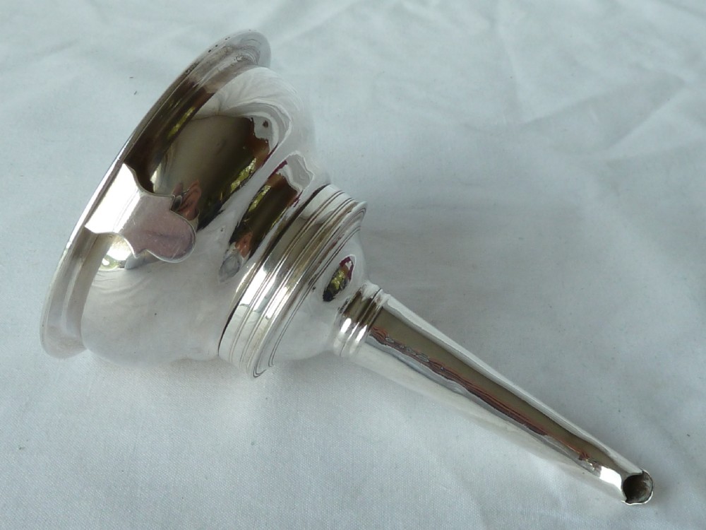 A Georgian sterling silver three-piece wine funnel shown disassembled into a pierced ring, curved spout base, and silver bowl. View V