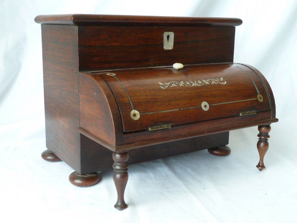 A Victorian novelty stationery box constructed from dark rosewood in the shape of an upright piano, adorned with mother-of-pearl floral inlay and turned front legs.