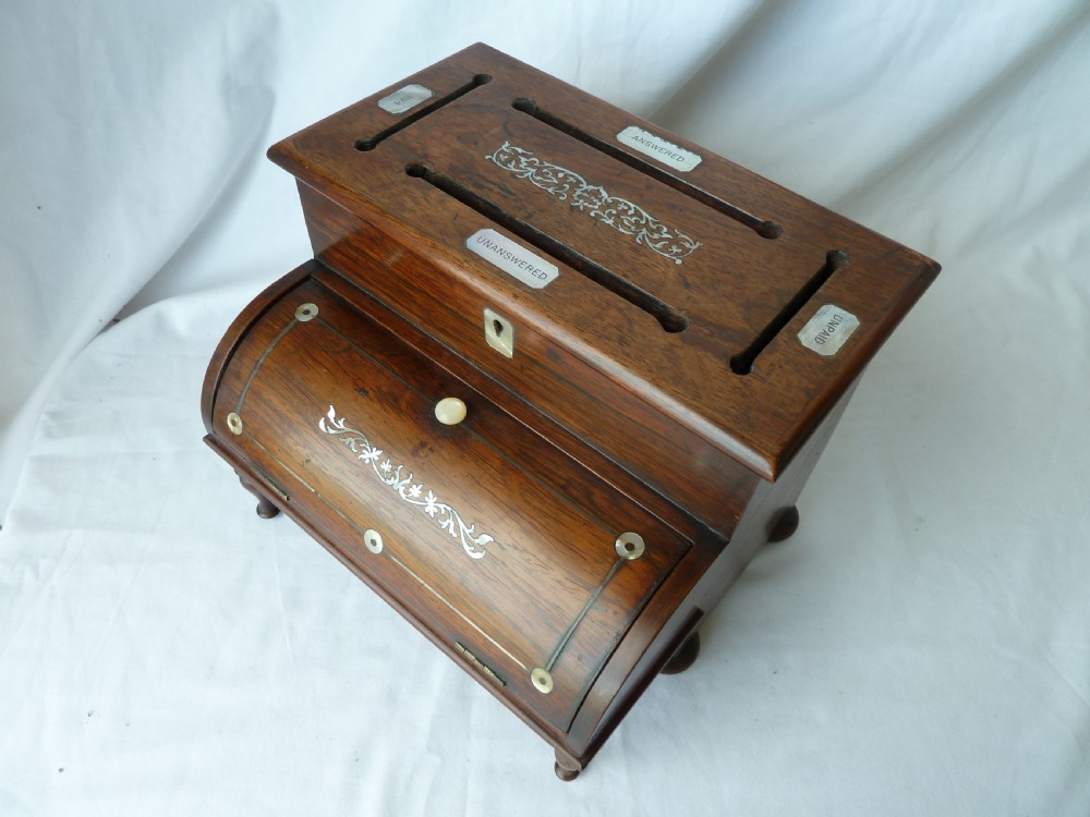 A Victorian novelty stationery box constructed from dark rosewood in the shape of an upright piano, adorned with mother-of-pearl floral inlay and turned front legs. View III