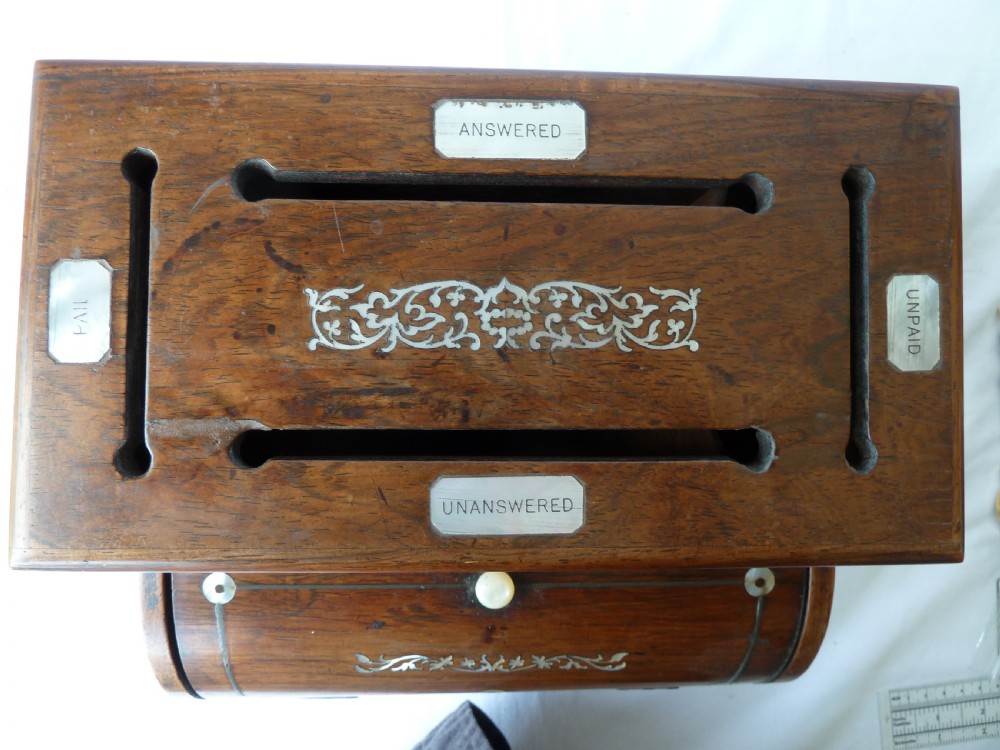 A Victorian novelty stationery box constructed from dark rosewood in the shape of an upright piano, adorned with mother-of-pearl floral inlay and turned front legs. View IV