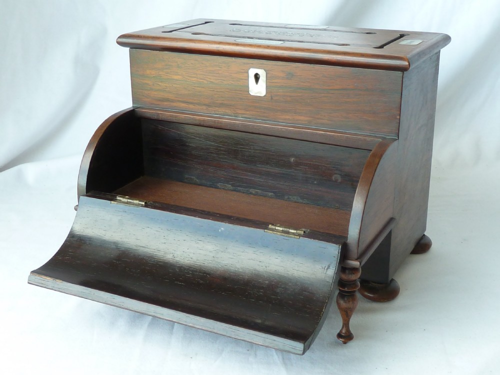 A Victorian novelty stationery box constructed from dark rosewood in the shape of an upright piano, adorned with mother-of-pearl floral inlay and turned front legs. View V