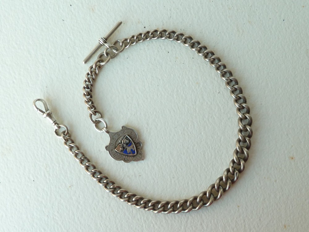 A solid sterling silver Victorian Albert pocket watch chain featuring curb links, a T-bar, swivel clasp, and a heraldic enamelled shield fob.