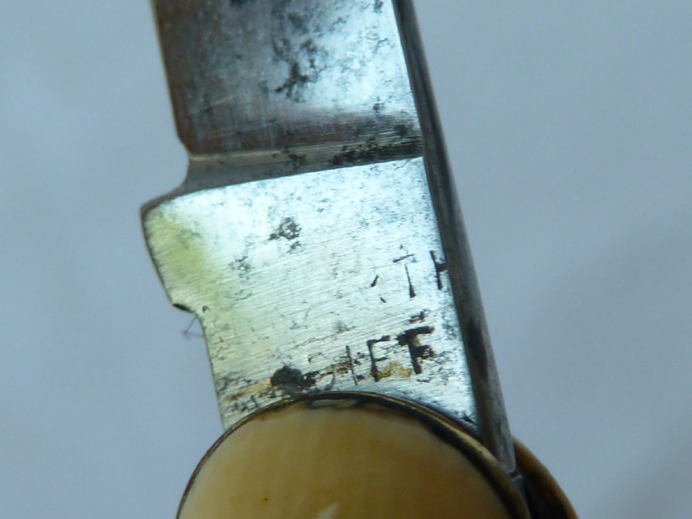 A cream ivorine folding pocket knife moulded in the shape of a female nude figure with two partially opened steel blades. View IV