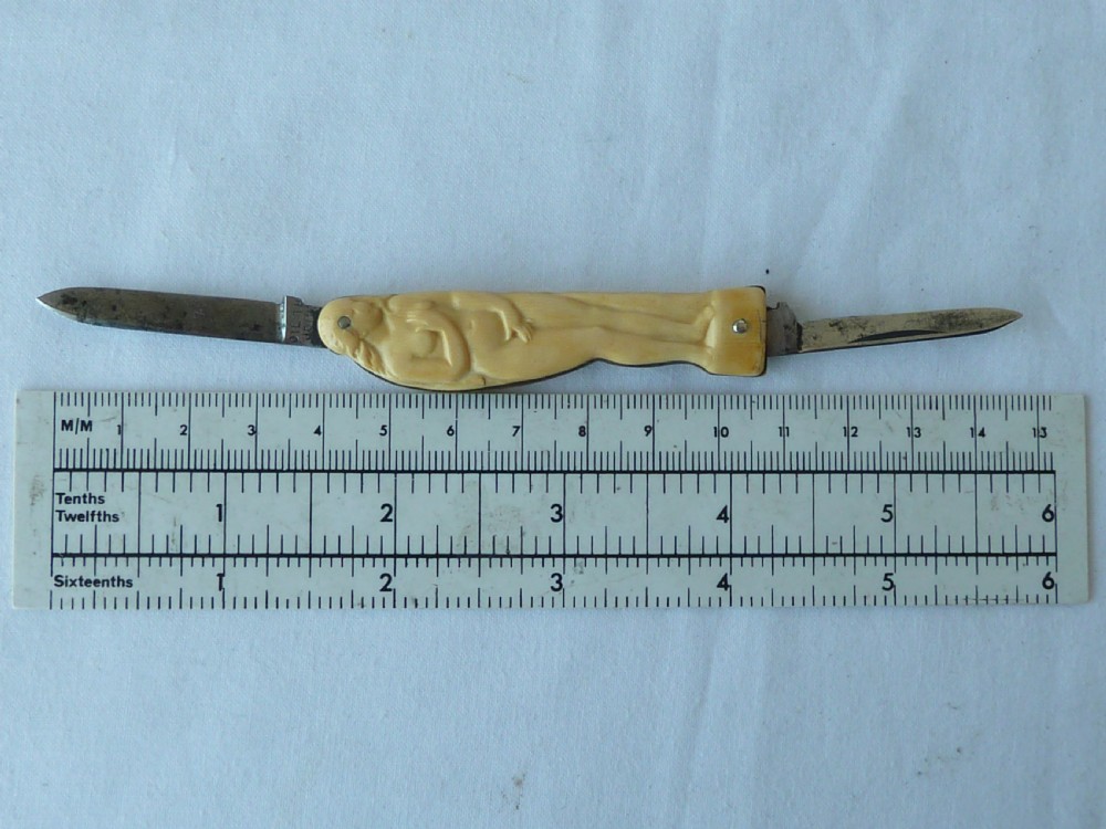 A cream ivorine folding pocket knife moulded in the shape of a female nude figure with two partially opened steel blades. View V