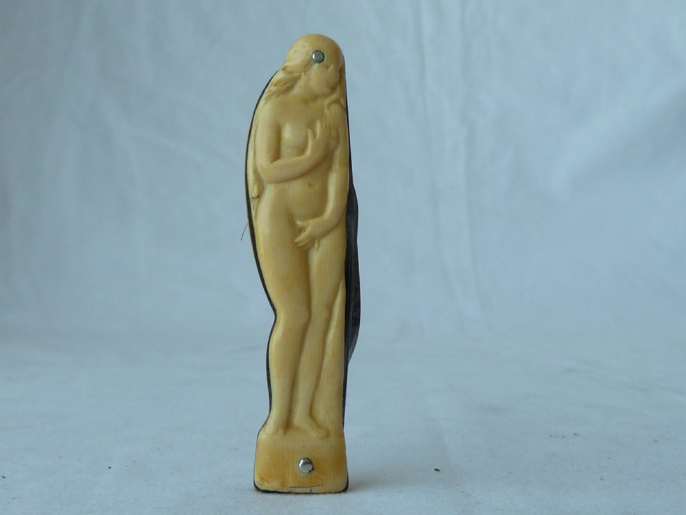 A cream ivorine folding pocket knife moulded in the shape of a female nude figure with two partially opened steel blades. View VI