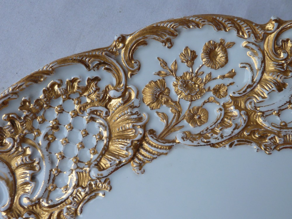 A circular white Meissen porcelain dish featuring a hand-painted illustration of two birds on branches, surrounded by a heavily gilded and pierced Rococo rim. View V